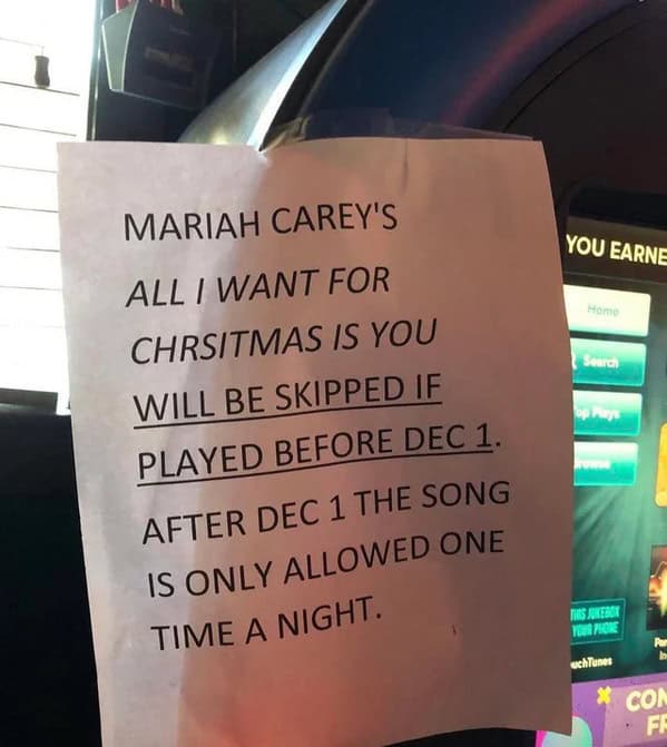A funny sign on a jukebox, banning Mariah Carey's "All I Want for Christmas" before December 1st.