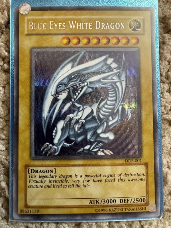 A 90s toy image showing a holographic Blue-Eyes White Dragon Yu-Gi-Oh card