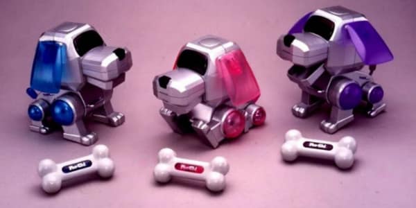 In this 90s toy picture, three Poo-Chi robotic dogs sit with magnetic bones.
