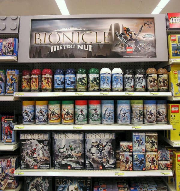 A 90s toy store display showing shelves stocked with LEGO Bionicle canisters.