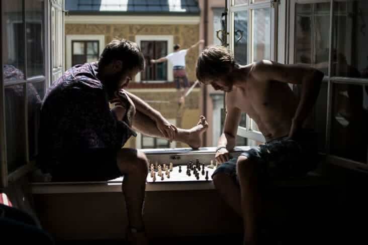 An accidental renaissance painting image of two shirtless men playing chess on a window ledge with dramatic lighting