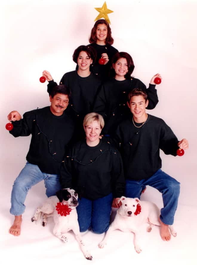 An awkward family christmas photo of a family stacked in a pyramid shape wearing black sweaters