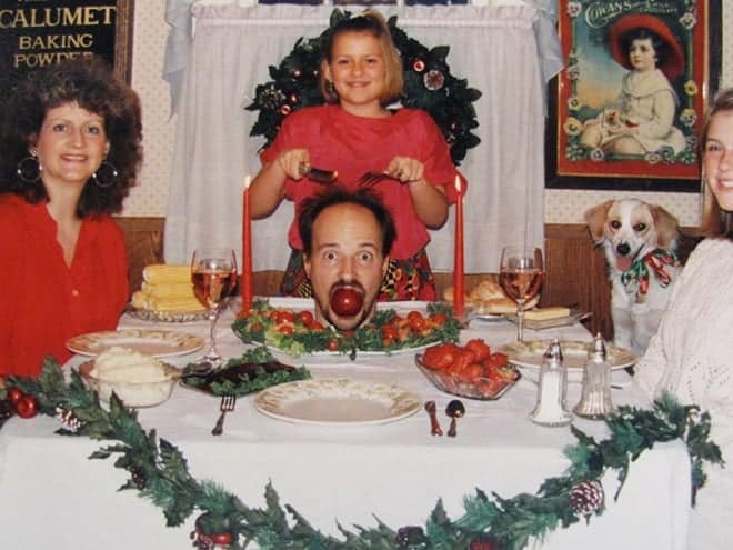An awkward family christmas photo featuring a man's head served on a platter for dinner