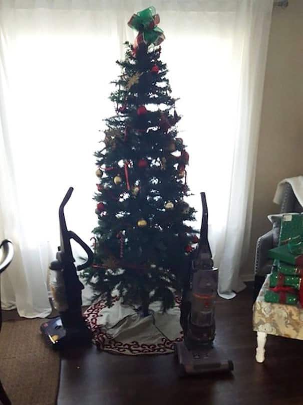 A funny picture of cat proofing christmas tree using two vacuum cleaners as guards.