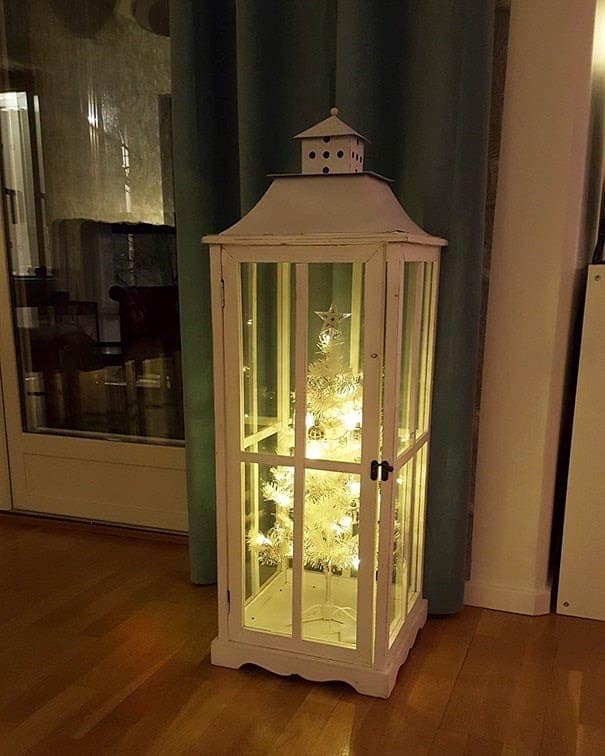 A cat christmas tree enclosed inside a white wooden lantern cabinet.