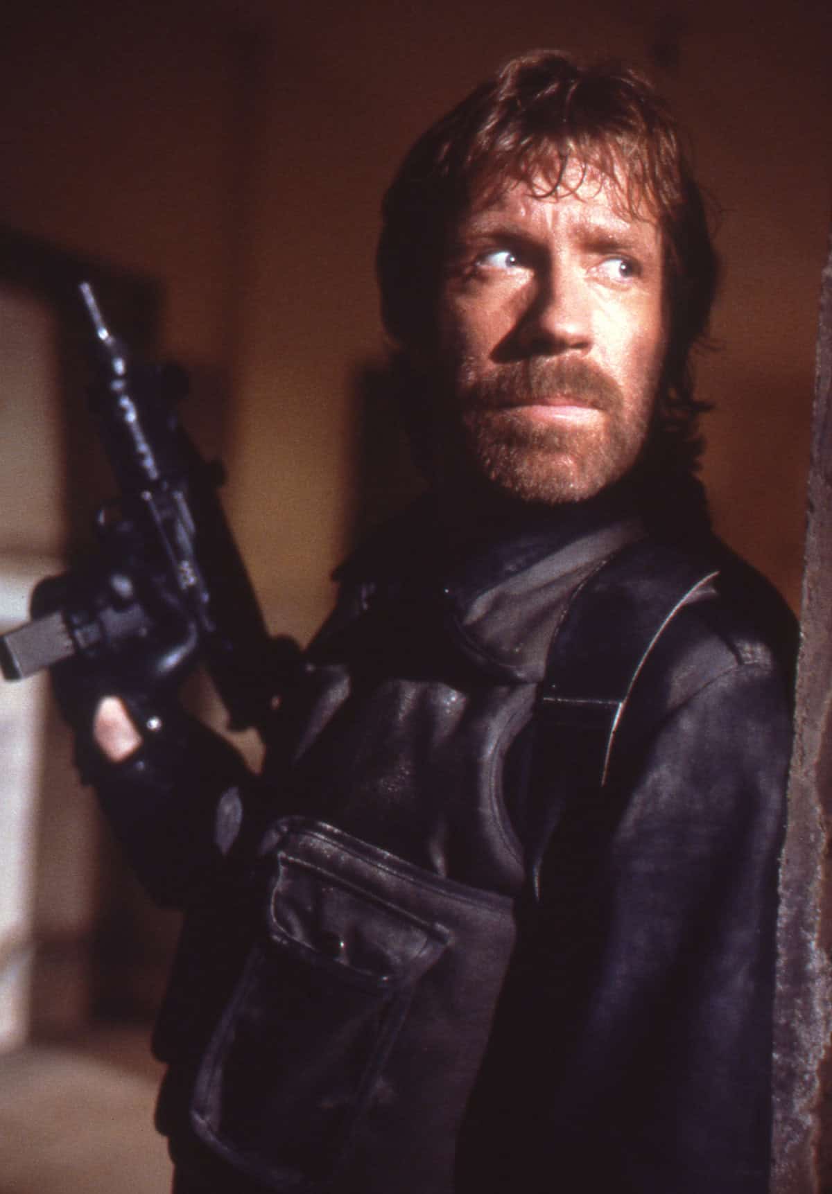 A classic action movie still of Chuck Norris holding a machine gun.