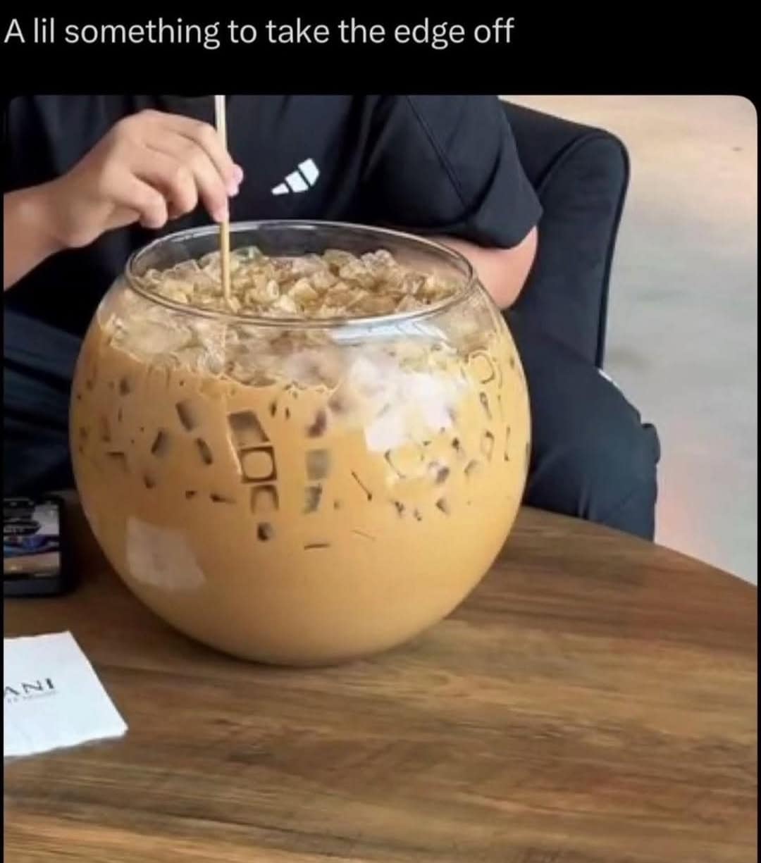 A funny meme showing a person drinking iced coffee from a massive fish bowl size glass.