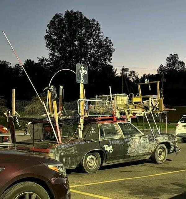 A classic meme image of a car covered in junk and pipes looking like a Mad Max vehicle.