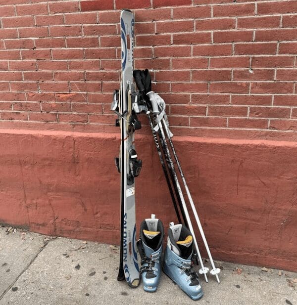 A curb alert showing a full set of skis boots and poles leaning against a brick wall.
