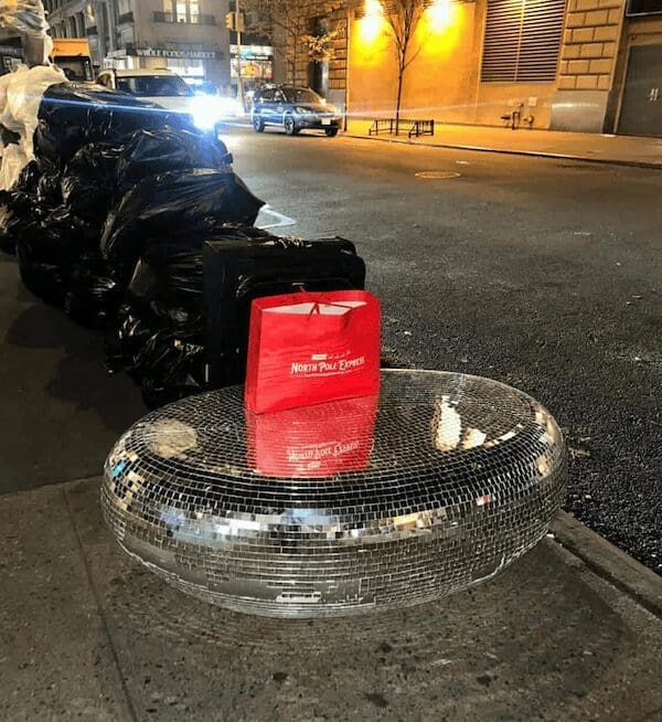 A curb alert of a shiny disco ball shaped coffee table next to trash bags.