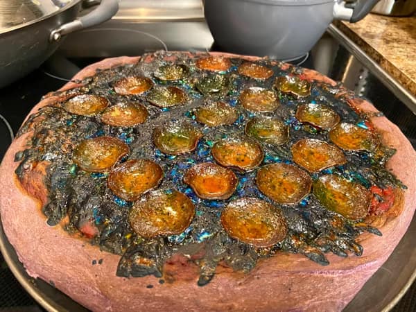 Burnt pizza that looks purple and radioactive used as a cursed image