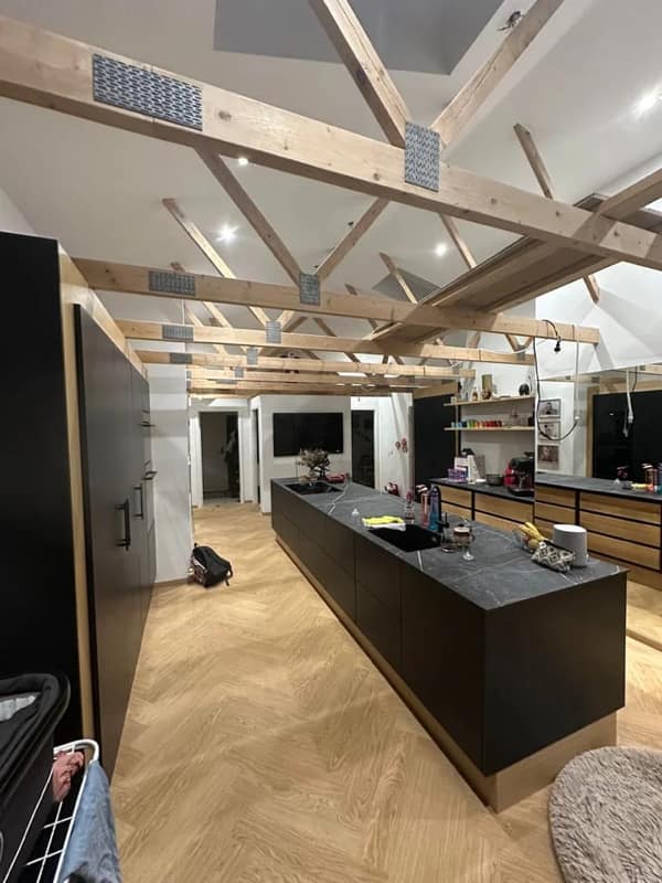 A diy fail kitchen renovation with wooden beams installed in a chaotic non structural pattern.