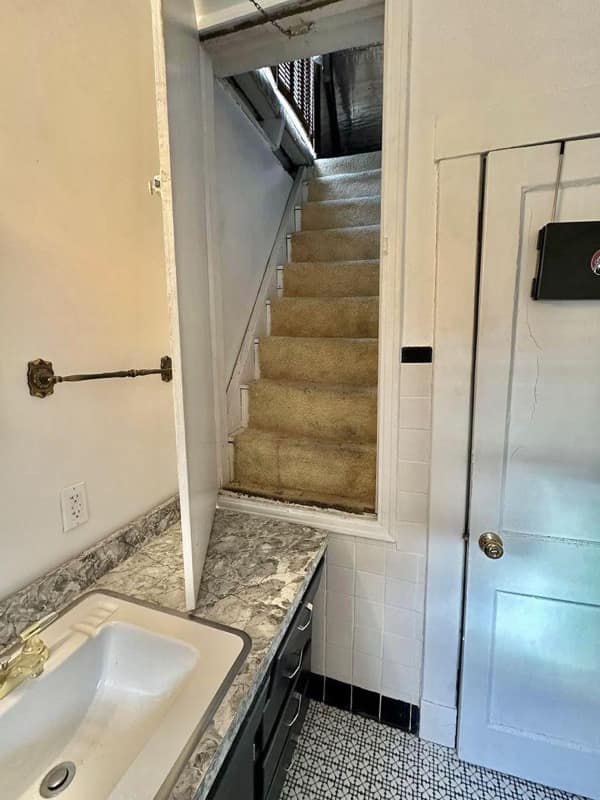 A di-why staircase leading directly into a wall with a tiny door cut out at the top