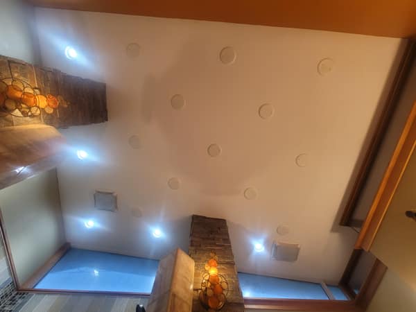 A diy fail ceiling with recessed lights installed in a completely random scattered pattern.