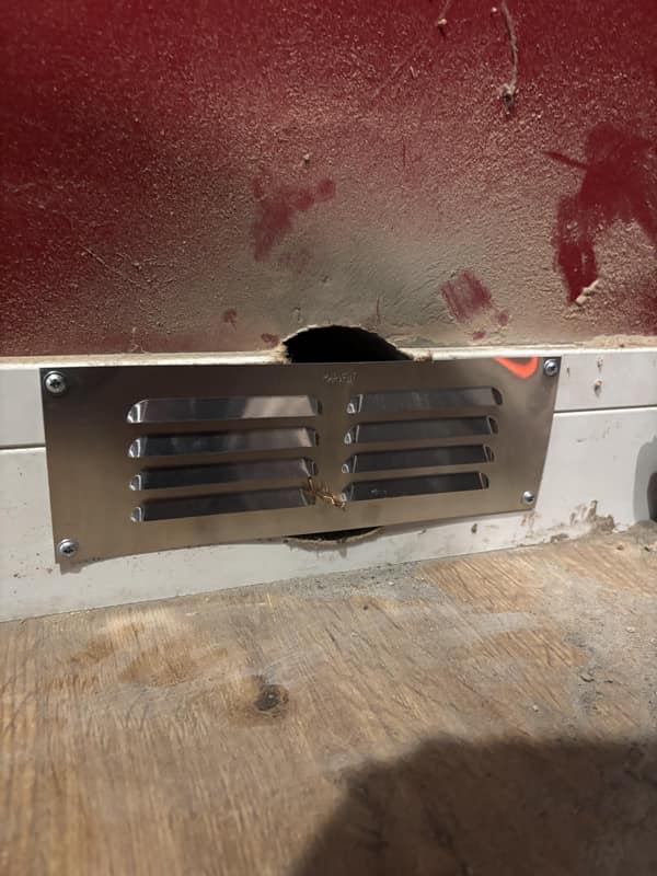 A di-why ventilation cover cut with tin snips to fit around a poorly placed hole.
