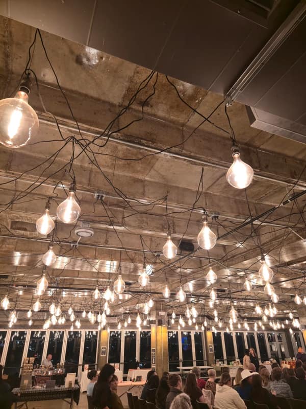 A di-why lighting setup with a chaotic spiderweb of black wires hanging from a concrete ceiling.