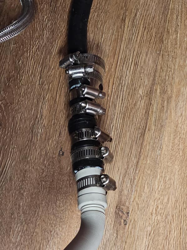 A diy fail plumbing repair using ten metal hose clamps on a single connection.