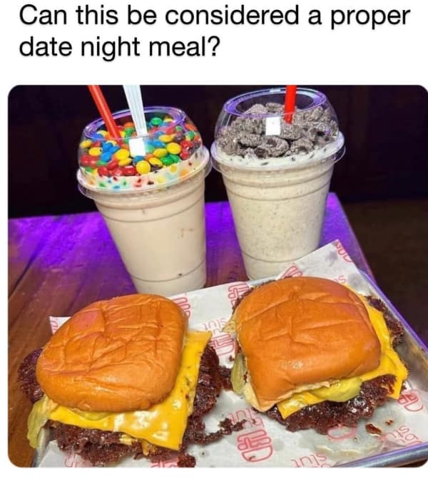 Tray with two cheeseburgers and loaded milkshakes with candy toppings.