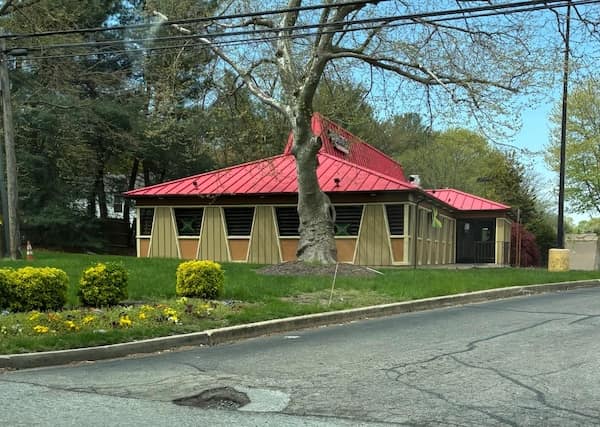Building with bright red metal roof and trapezoid windows is a former Pizza Hut.