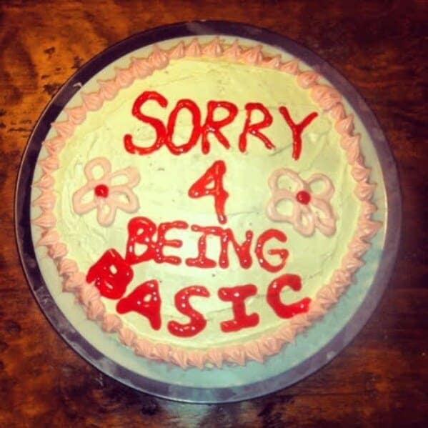 White cake with pink frosting text apologizing for being basic.