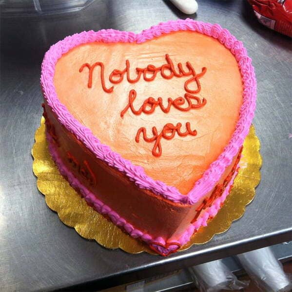 Heart shaped cake with red text saying nobody loves you.