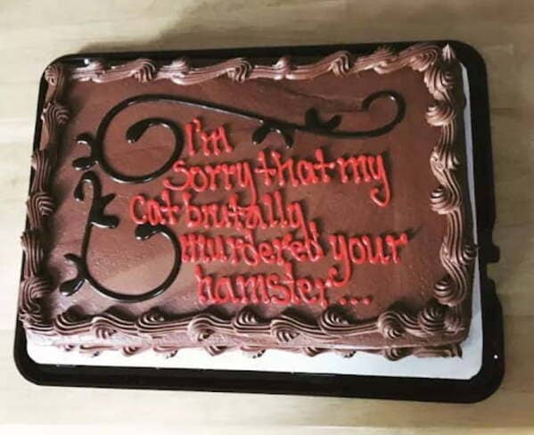 Chocolate cake with red text apologizing for cat murdering hamster.