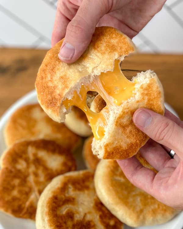 A funny cheese meme showing a satisfying cheese pull from a bread roll.