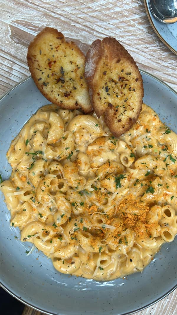 A funny cheese meme of a plate of creamy macaroni and cheese with garlic bread.