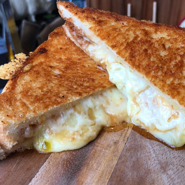 A funny cheese meme of a grilled cheese sandwich cut in half with melted cheese oozing out.