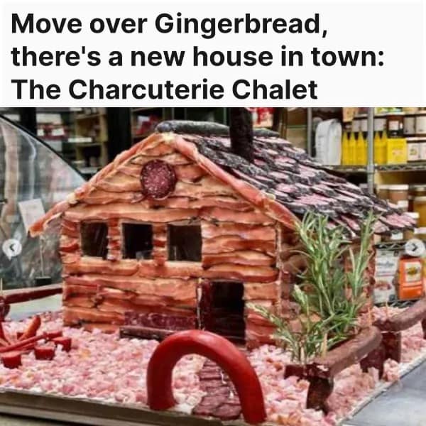 Miniature house made of salami and crackers labeled The Charcuterie Chalet.
