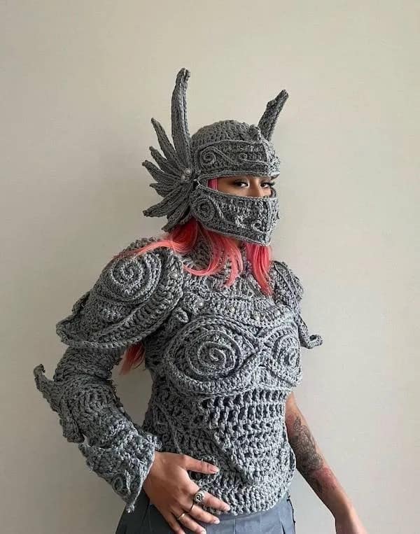 Person wearing intricate gray crochet knight armor helmet and chest piece costume.