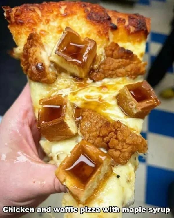 Slice of pizza topped with fried chicken and syrup-filled mini waffles.