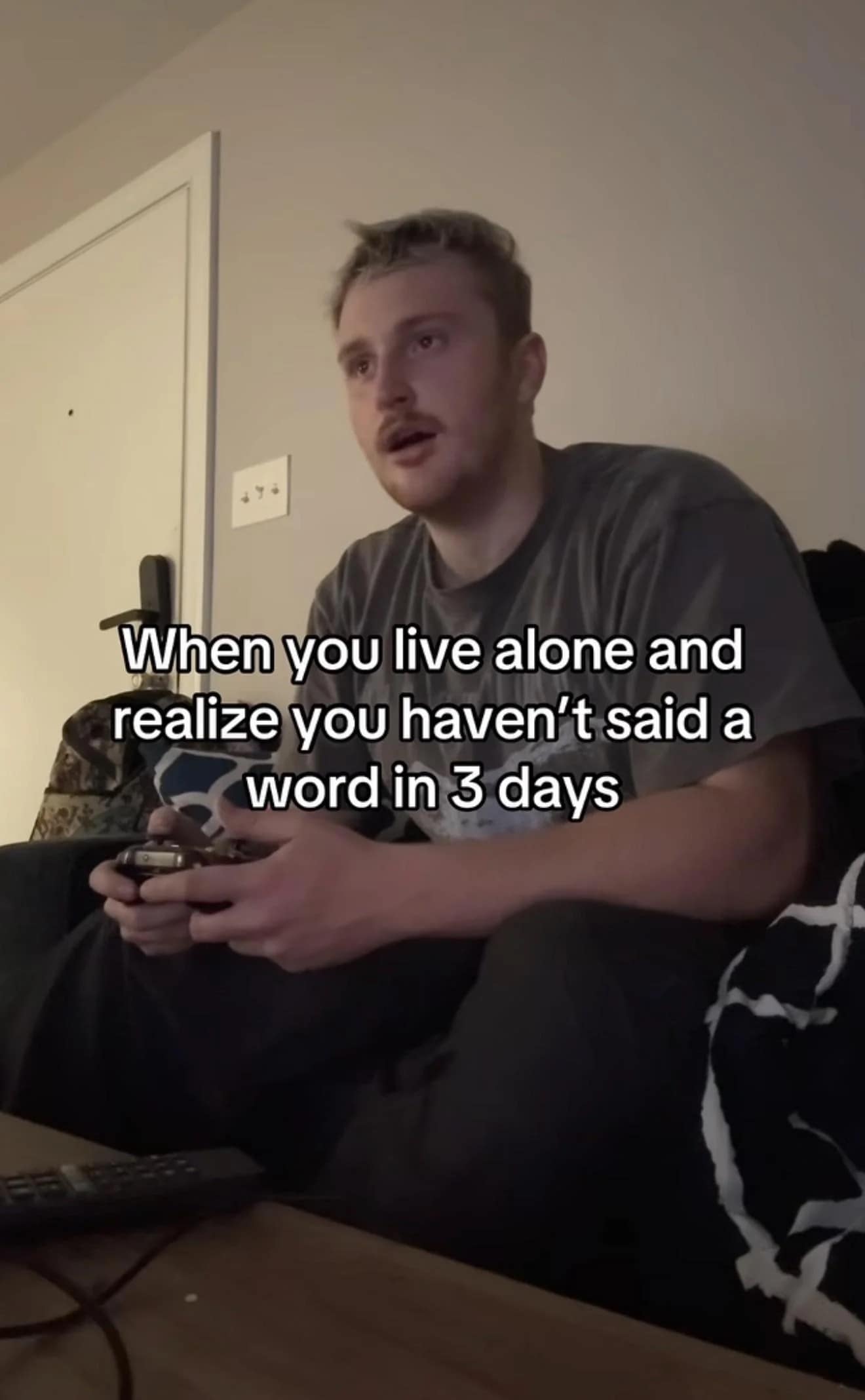 Man sitting on a couch holding a video game controller staring blankly.