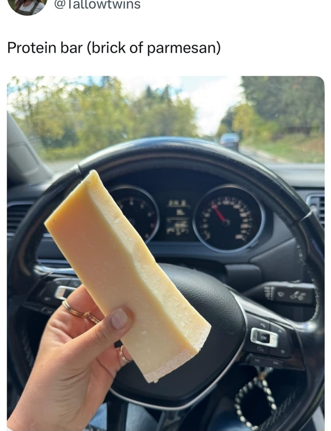 This funny pic displays a block of Parmesan cheese being eaten like a protein bar in a car