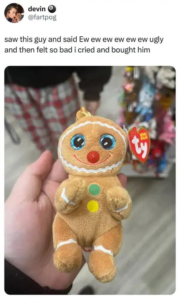 Small gingerbread man plush toy with large, sparkly blue eyes held in hand.