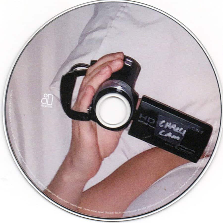Hand holding a camcorder that is recording another camcorder on a circular disc.