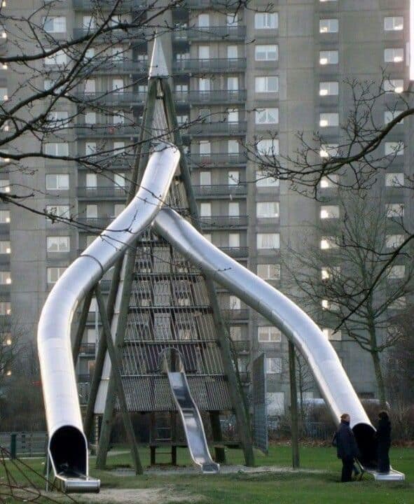 Large metal playground slide structure with dangerously steep and high tubes.