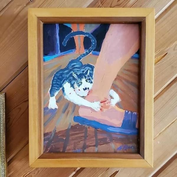 A funny thrift store find painting capturing the exact moment a cat attacks a human ankle