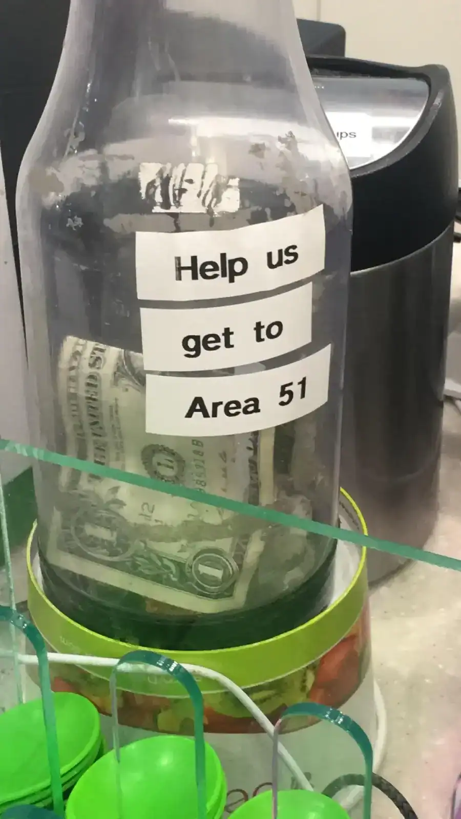 A funny tip jar bottle with a label asking for help to get to Area 51.