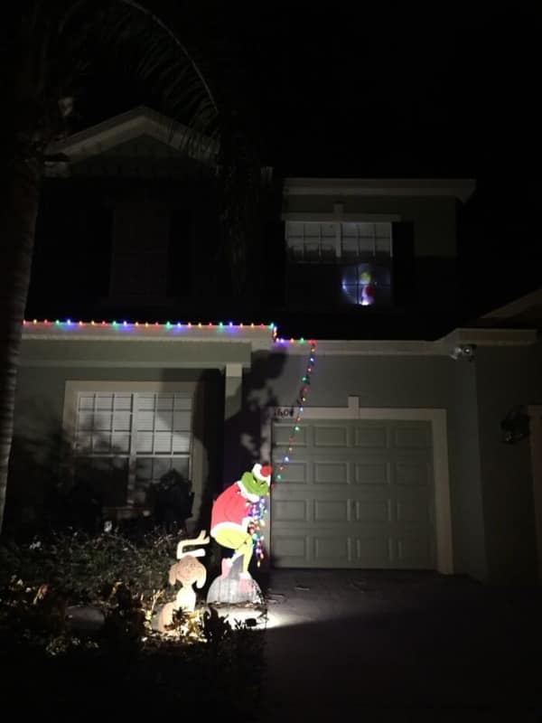 Grinch yard decoration pulling single string of Christmas lights from undecorated house.