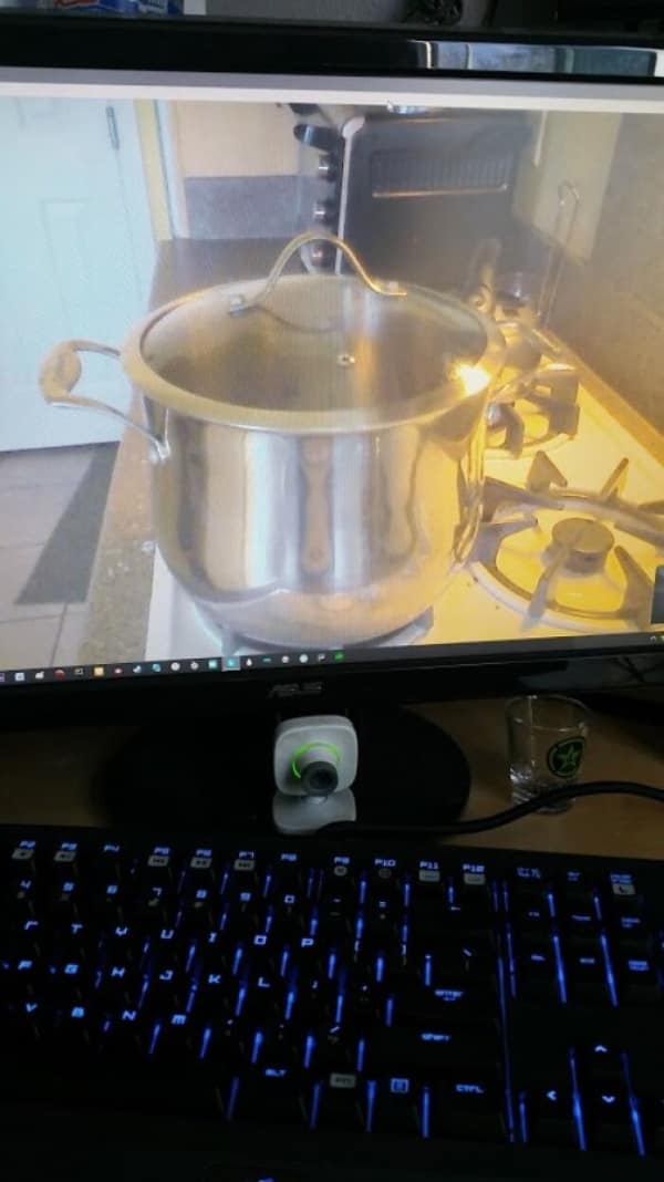 Computer monitor displaying webcam feed of pot boiling on stove top.