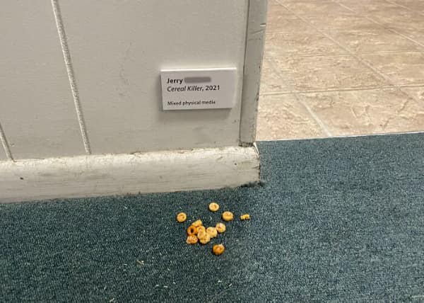 Spilled cereal loops on carpet labeled with museum art card titled Cereal Killer.