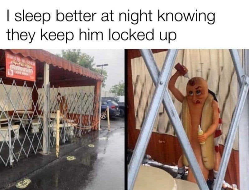 A funny meme of a terrifying hot dog statue putting ketchup on itself behind a gate.