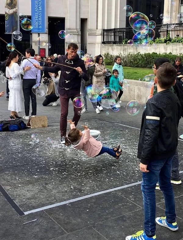 A funny meme photo of a child falling mid-air while trying to catch a giant bubble