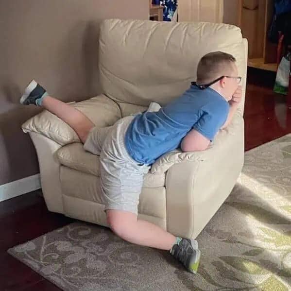 A funny meme of a boy stuck sideways inside a beige recliner chair.