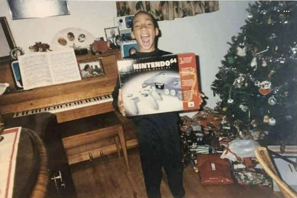 A retro christmas photo of a boy receiving a Nintendo 64 console.