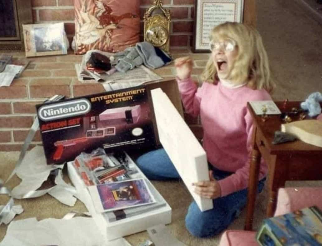 A retro christmas photo of a girl reacting to a Nintendo NES gift.