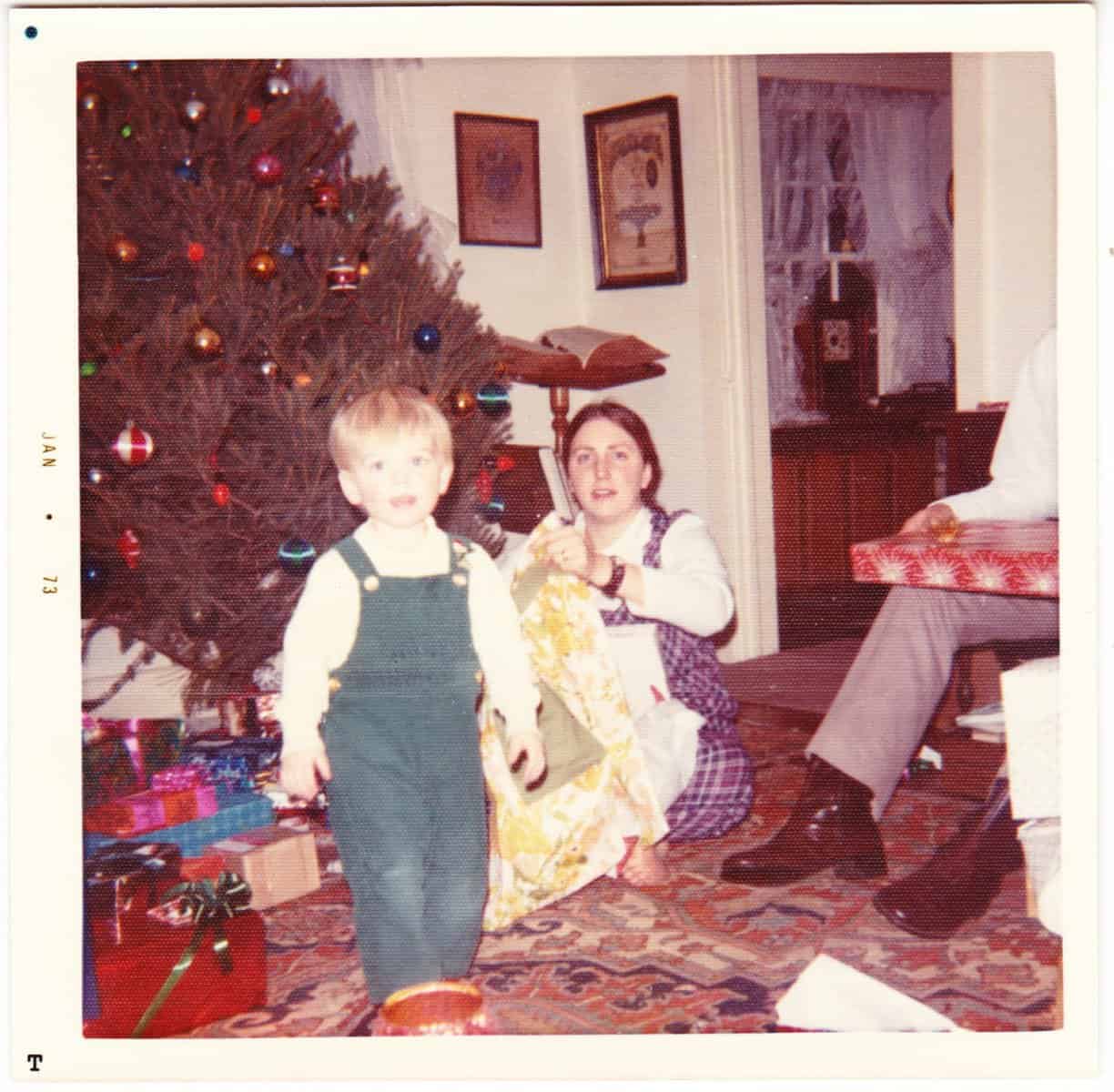 A retro christmas photo of a toddler in green overalls from 1973.