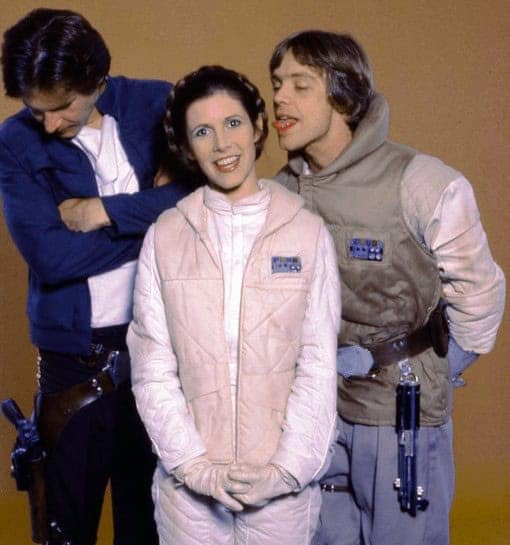 A Star Wars BTS photo of Mark Hamill sticking his tongue out at Carrie Fisher in Hoth gear.