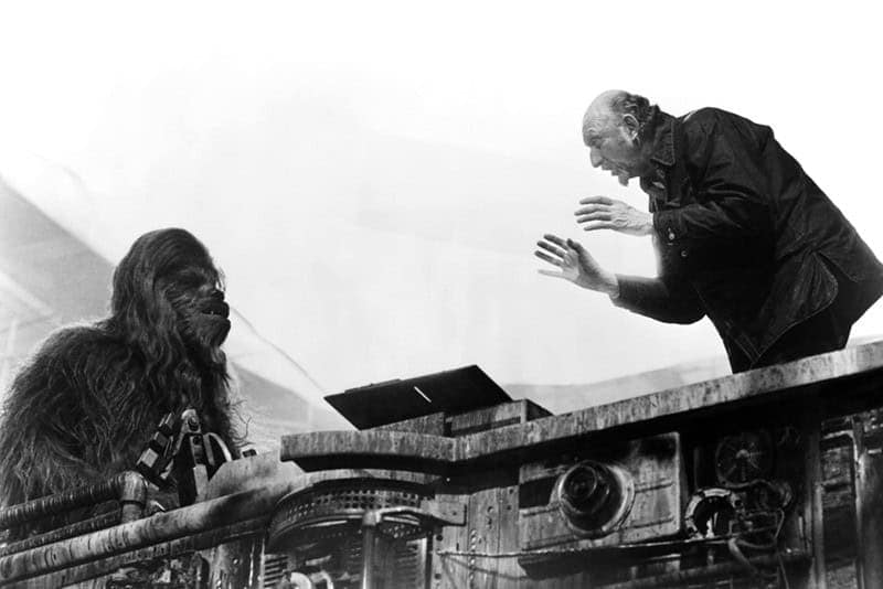 A Star Wars BTS photo of director Irvin Kershner giving instructions to Chewbacca on the freezing chamber set.